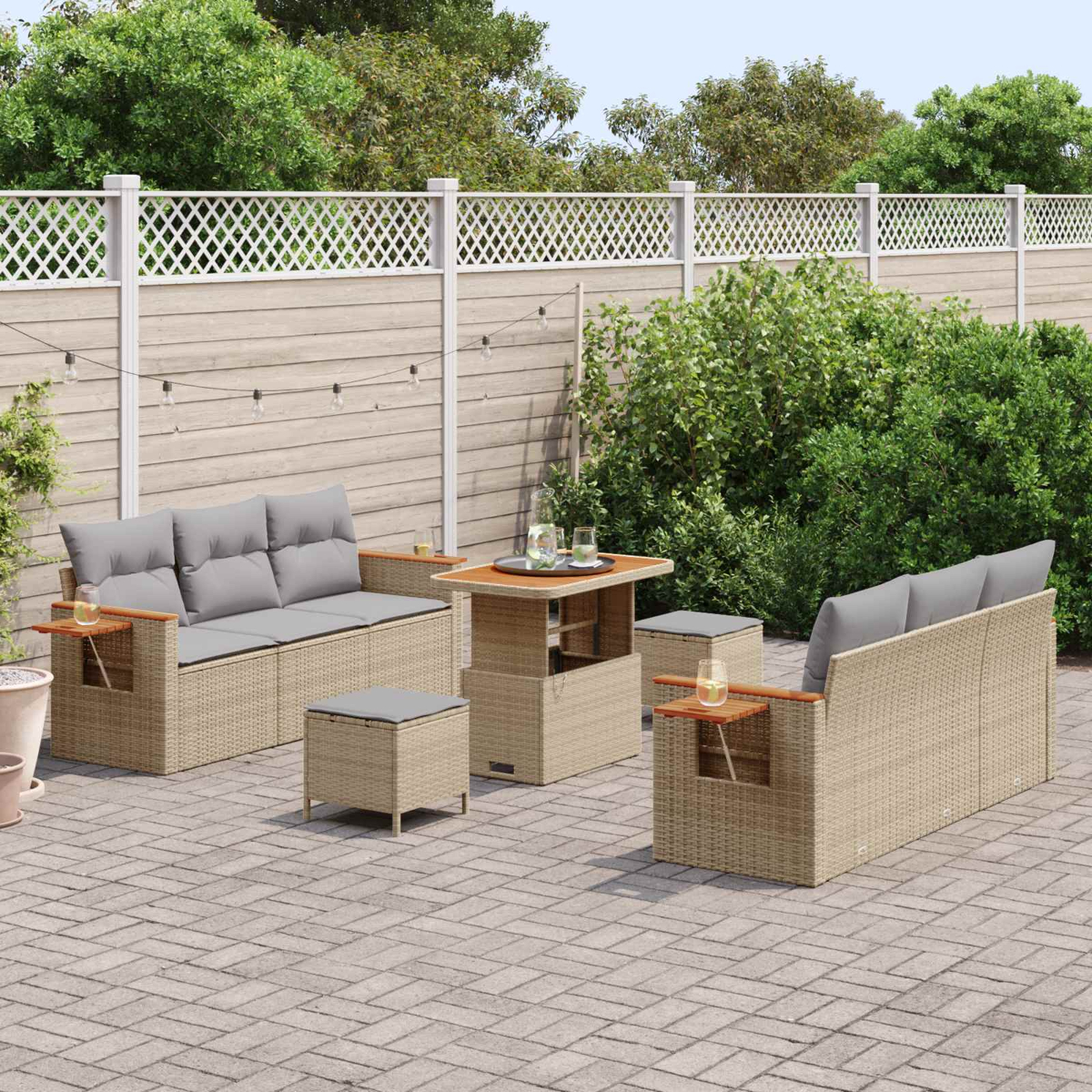Set di mobili da esterno in rattan con cuscini grigi su un patio pavimentato.