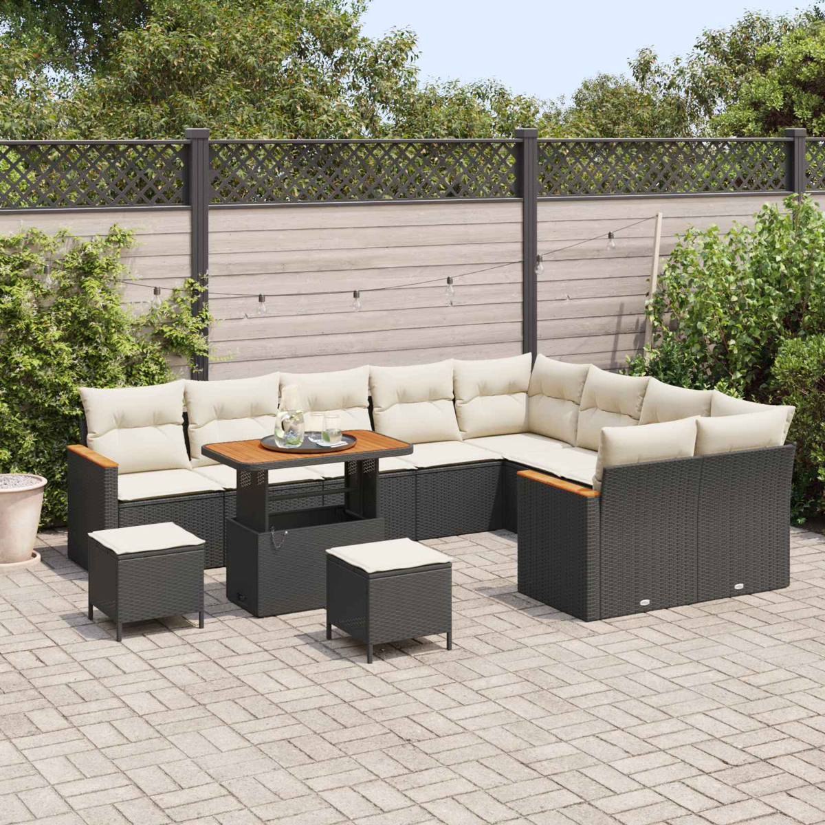 Ein dunkelgraues Lounge-Set aus Rattan mit cremefarbenen Kissen auf einer gepflasterten Terrasse.