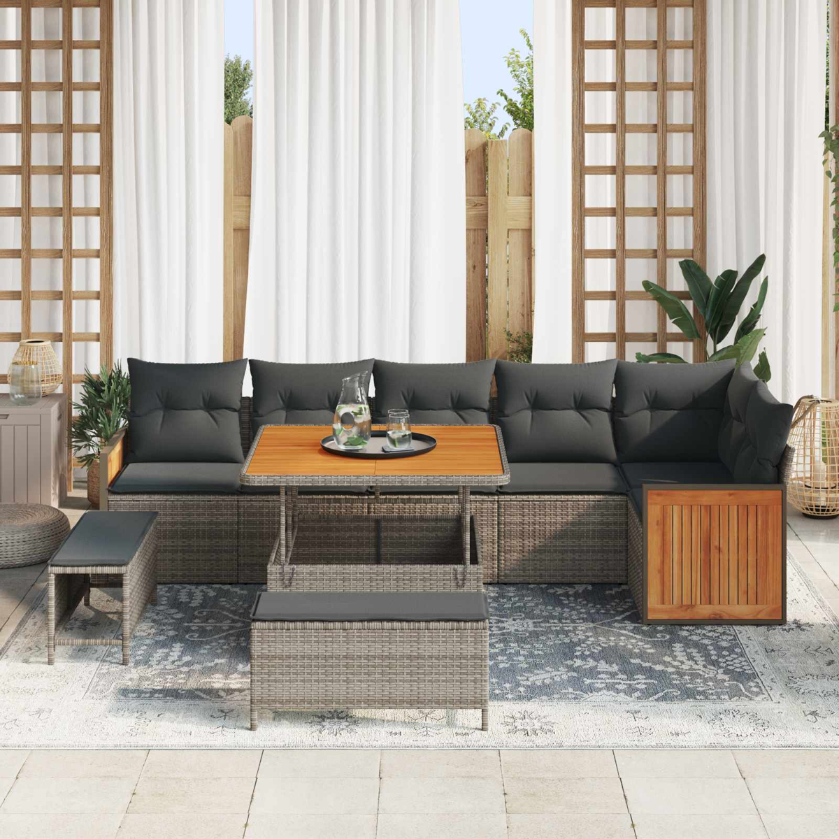 Muebles de salón de ratán gris con mesa de madera y cojines en un patio.