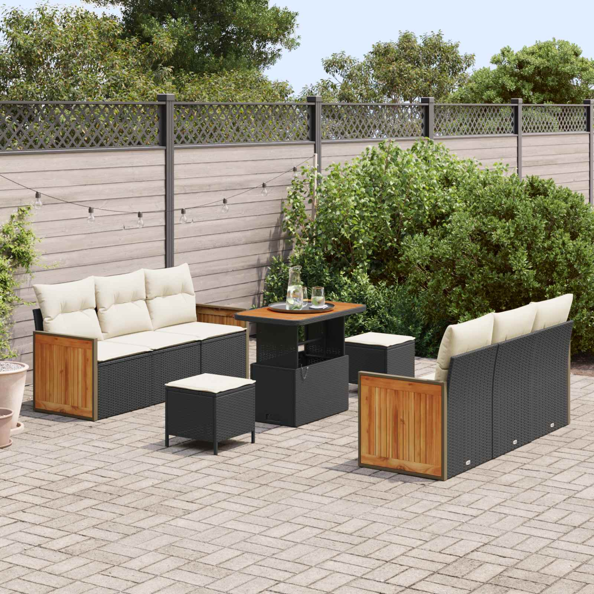 Garnitur für draußen mit Sofas, Hockern und Tisch auf einer gepflasterten Terrasse.