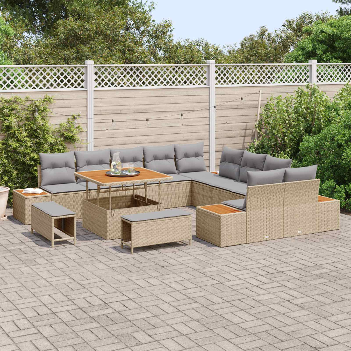 Un set lounge in rattan beige con cuscini grigi su un patio pavimentato.