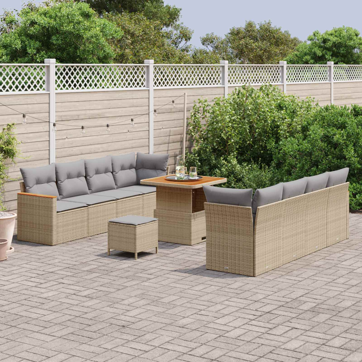 Muebles de jardín de ratán beige con cojines grises en patio pavimentado.