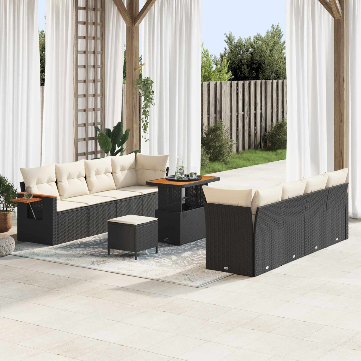 Outdoor-Sofa aus Rattan mit beigen Kissen auf einer Terrasse mit Tisch und Hocker.