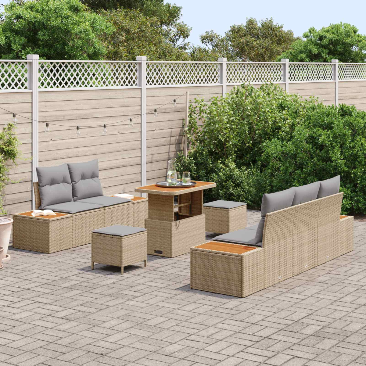 Ein Gartenmöbel-Set aus Rattan mit grauen Kissen auf einer gepflasterten Terrasse.