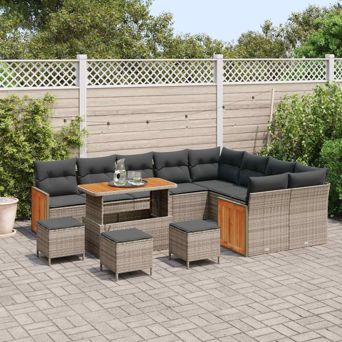 Ein graues Lounge-Set mit Tisch und Hockern auf einer gepflasterten Terrasse.
