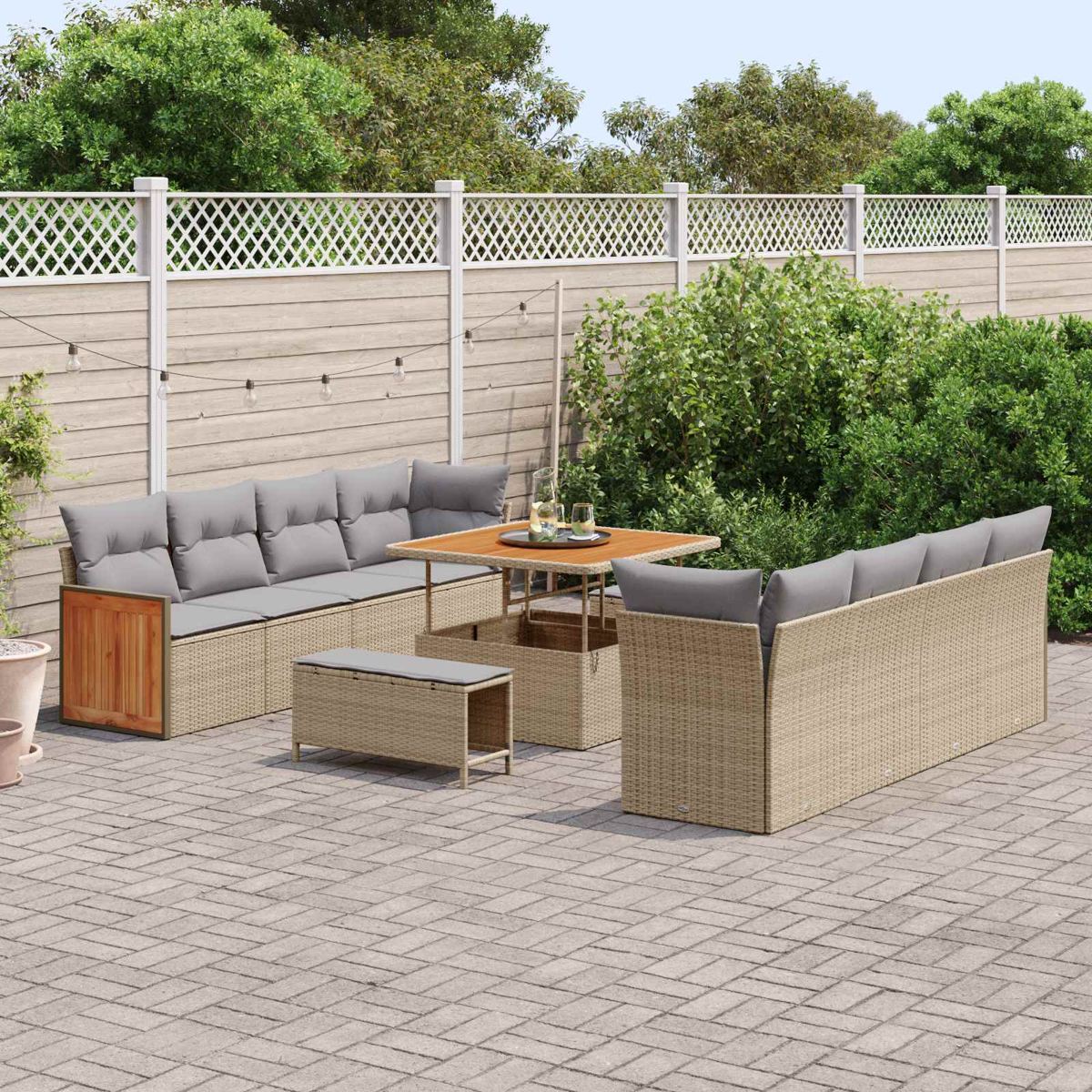 Gartenlounge mit beigen Rattan-Sofas, Tisch, Bank und Holzzaun.