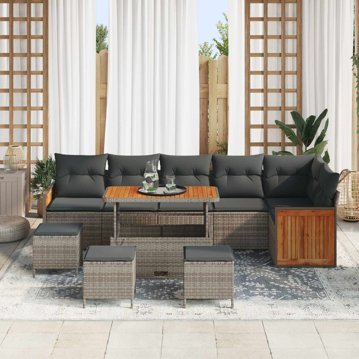 Geflochtene Lounge-Möbel mit grauen Kissen und Holztisch auf einem Teppich.