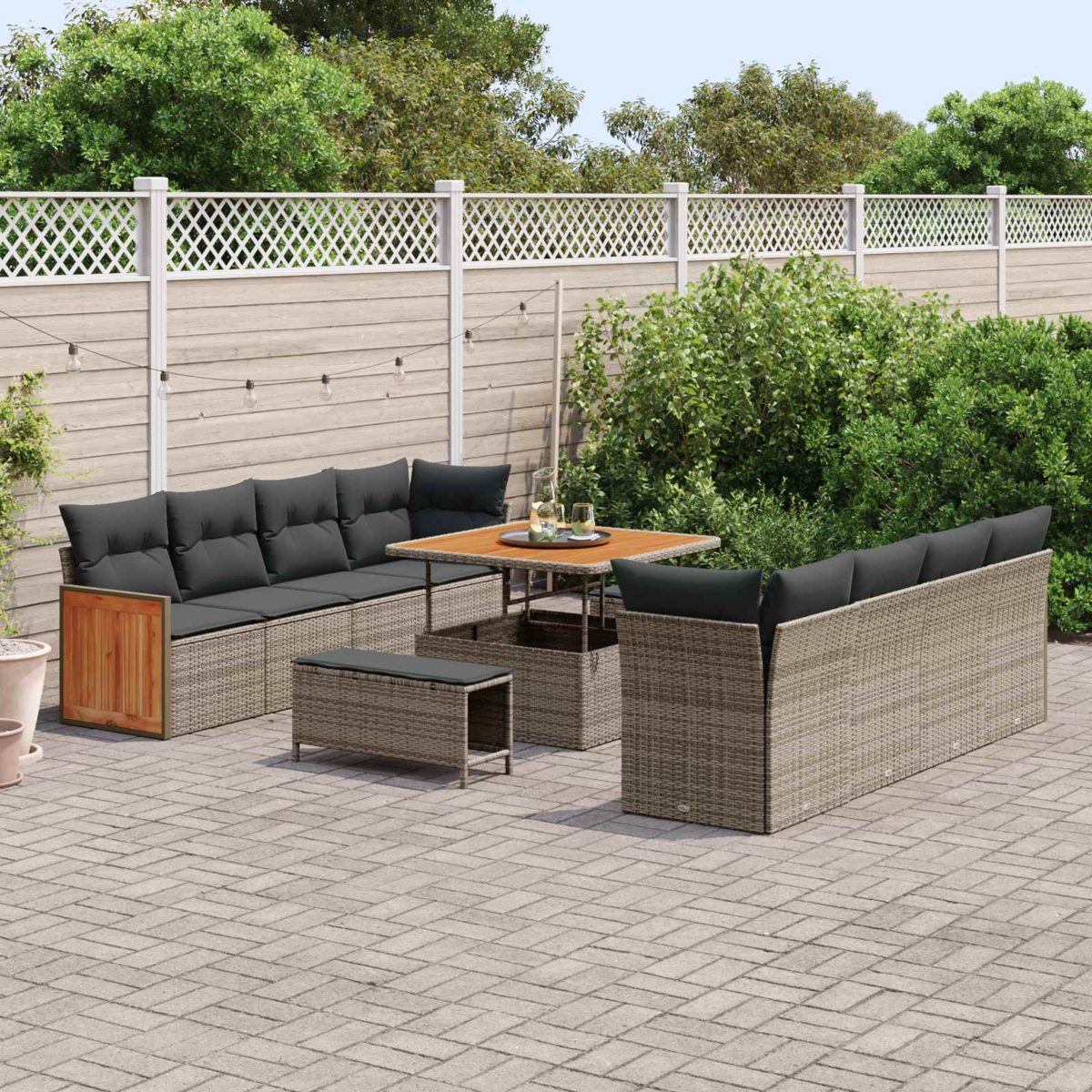 Un set di mobili da giardino in rattan con cuscini grigi e tavolo in legno su un patio.