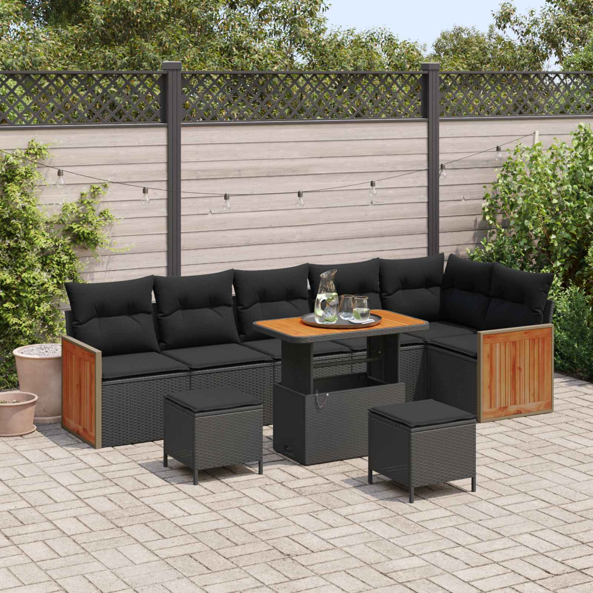 Ein graues Lounge-Set mit schwarzen Kissen und einem höhenverstellbaren Tisch auf einer Terrasse.