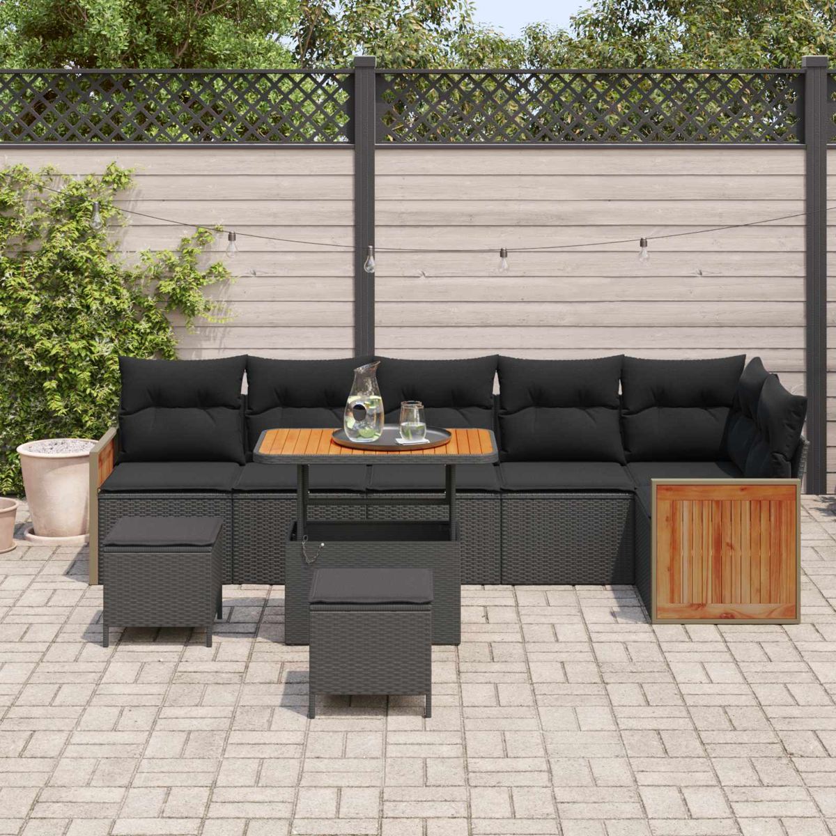 Dunkelgraue Loungemöbel mit schwarzen Polstern, Holztisch, Karaffe und Gläsern.
