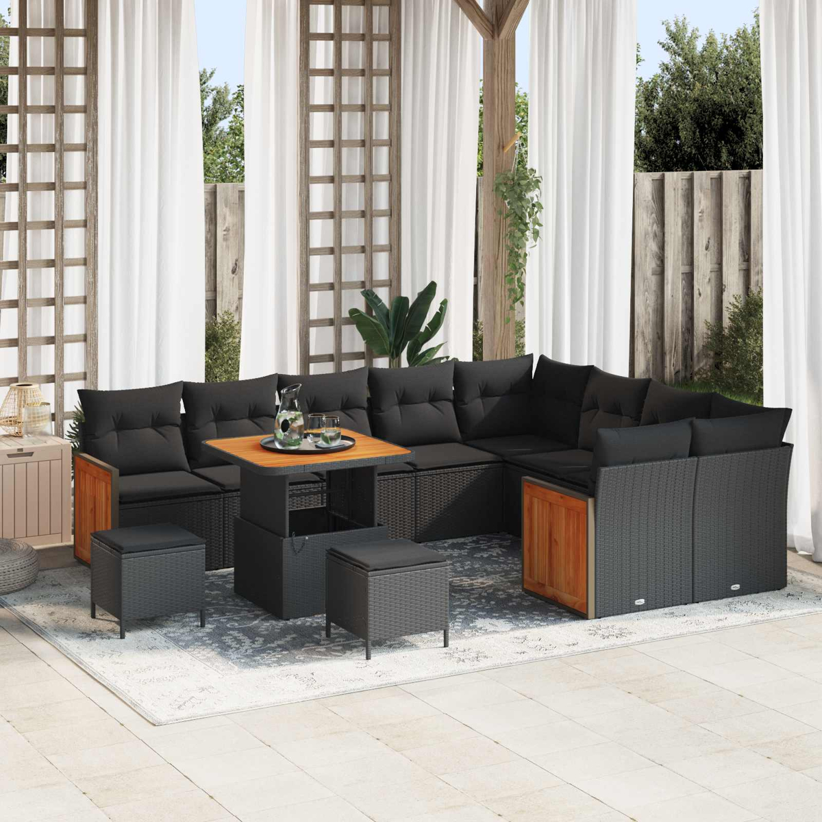 Ein dunkles Outdoor-Sofa mit Kissen und ein Tisch mit Hockern auf einer Veranda.