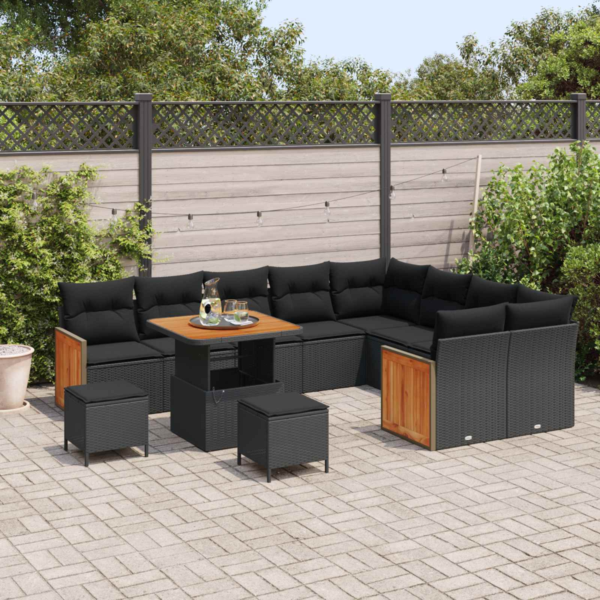 Dunkelgraues Lounge-Set mit schwarzen Kissen und Holzakzenten auf einer Kopfsteinpflasterterrasse.