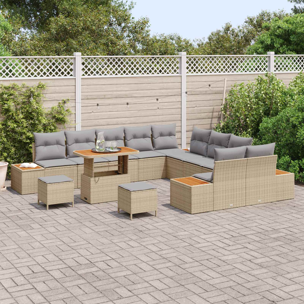 Un divano componibile in rattan beige con cuscini grigi su un patio pavimentato.