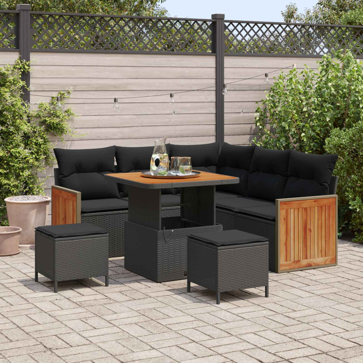 Gartenlounge mit schwarzem Ecksofa, höhenverstellbarem Tisch, zwei Hockern.