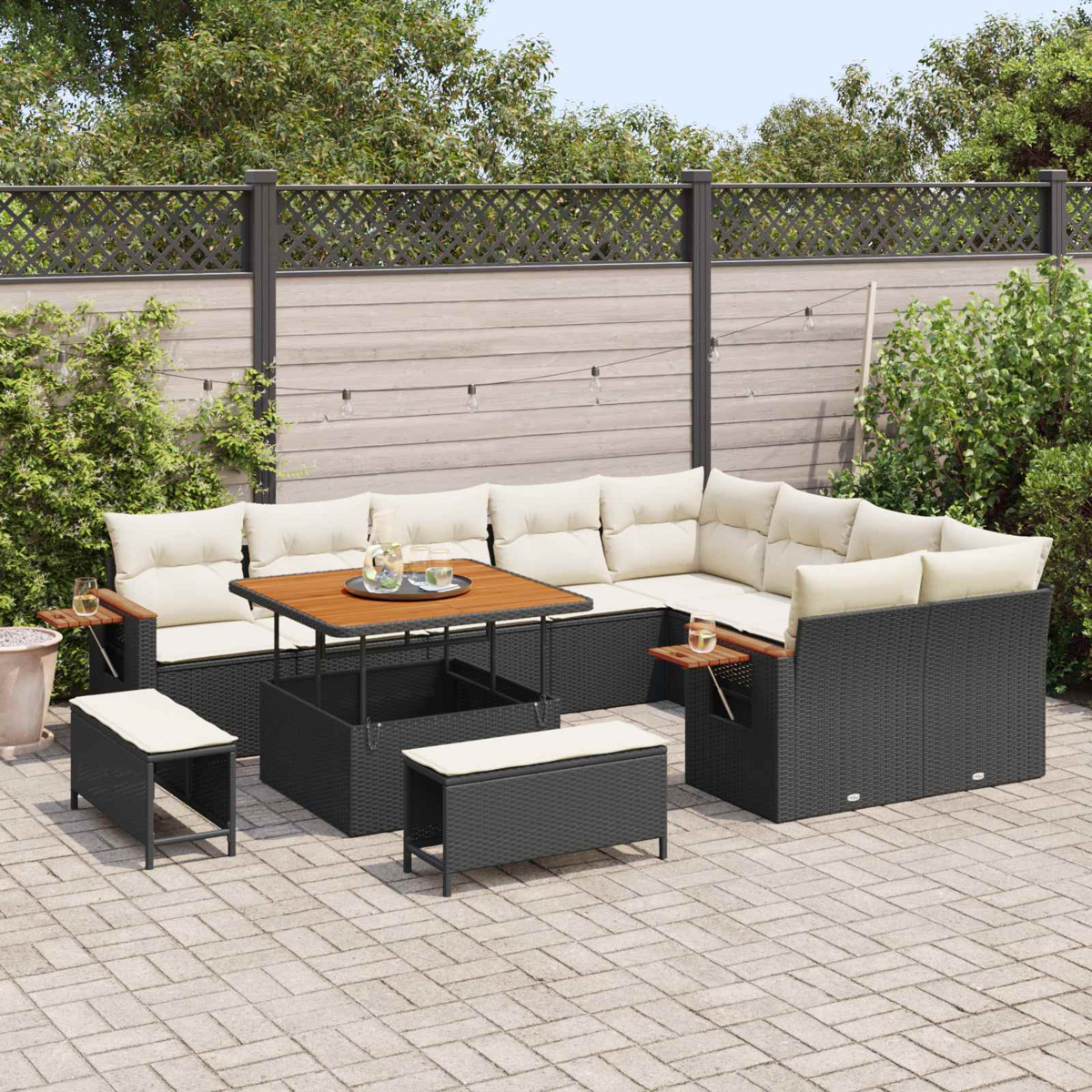 Ein dunkles Rattan-Sofa mit beigen Kissen und einem Holztisch auf einer gepflasterten Terrasse.