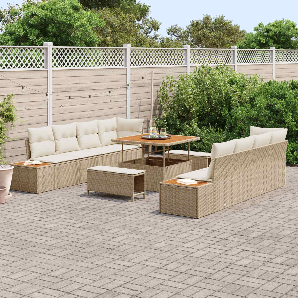 Ein beiger Rattansofa-Set mit Tisch auf einer gepflasterten Terrasse, umgeben von Grün.