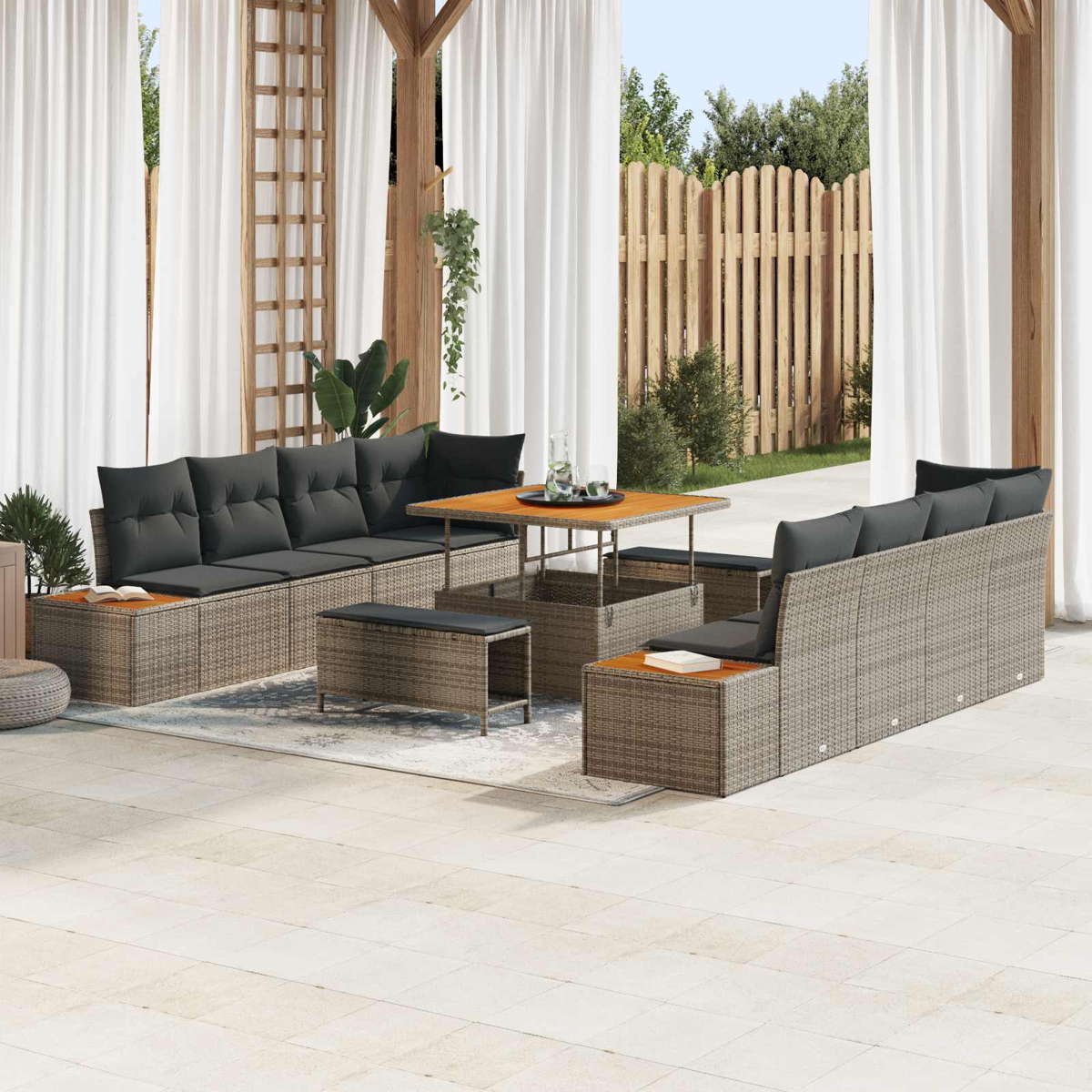 Geflochtene Lounge-Möbel mit grauen Kissen auf einer Terrasse, mit Holztisch und Pflanzen.