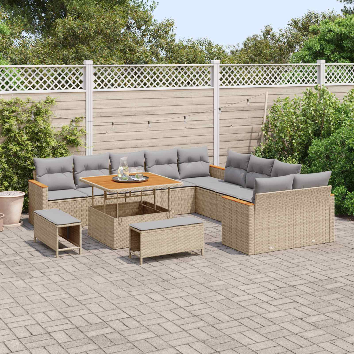 Geflochtene Lounge-Möbel mit grauen Kissen auf einer gepflasterten Terrasse.