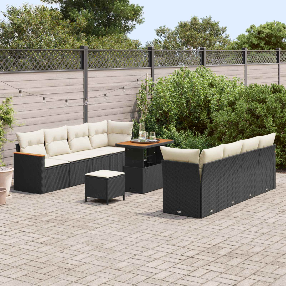 Ein dunkles Rattansofa mit hellen Kissen auf einer gepflasterten Terrasse.