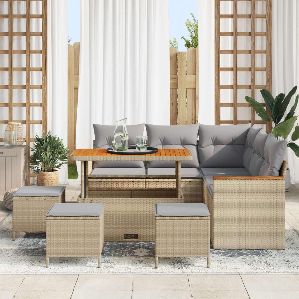 Muebles de exterior de mimbre con cojines grises, mesa con jarra y vaso.