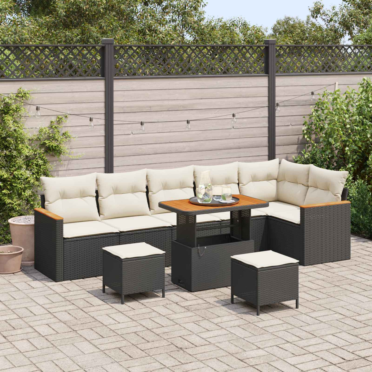 Ein dunkles Polster-Lounge-Set mit Tisch auf einer Pflasterterrasse, umgeben von Grün.