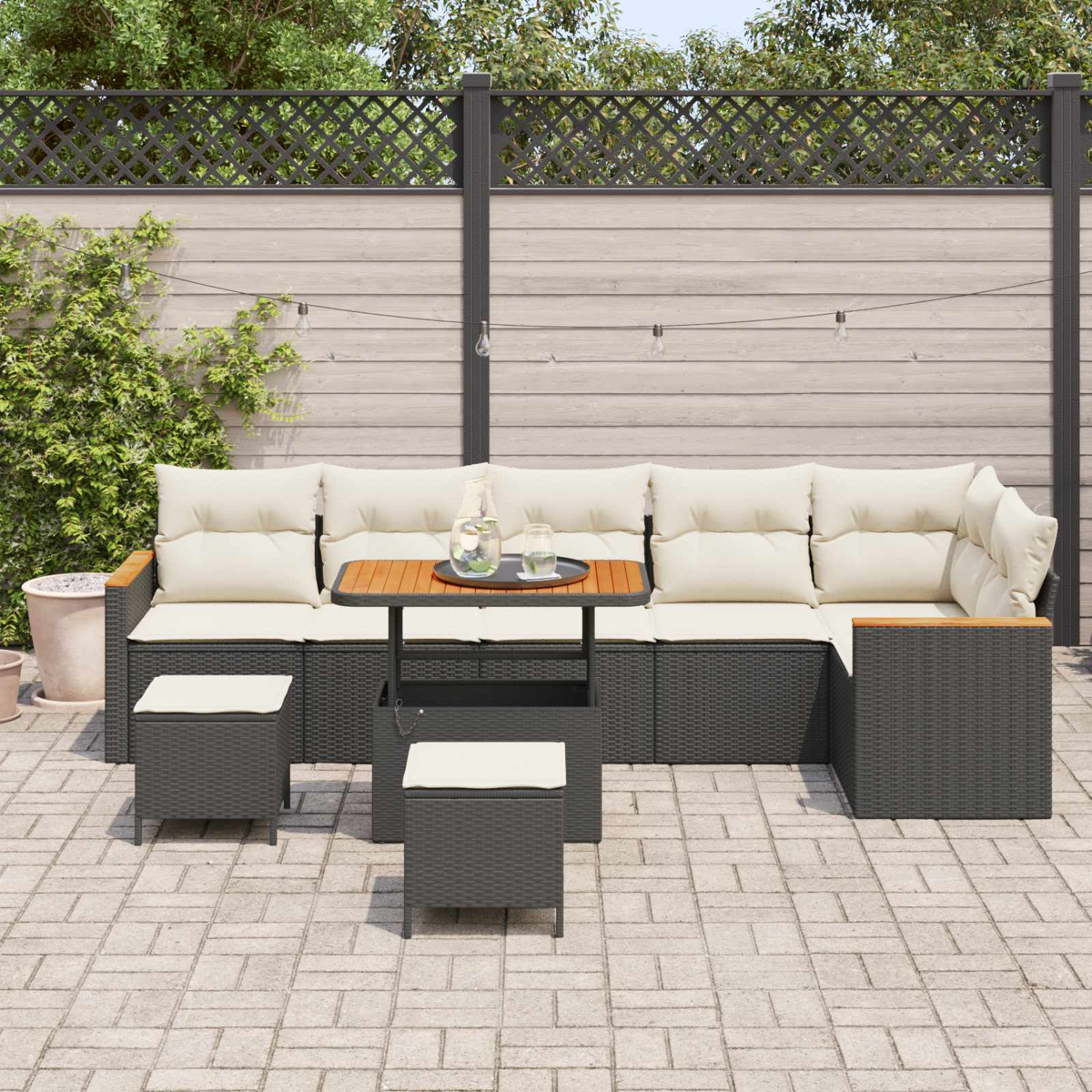Dunkelgraue Rattan-Lounge-Möbel mit cremefarbenen Kissen auf einer gepflasterten Terrasse.