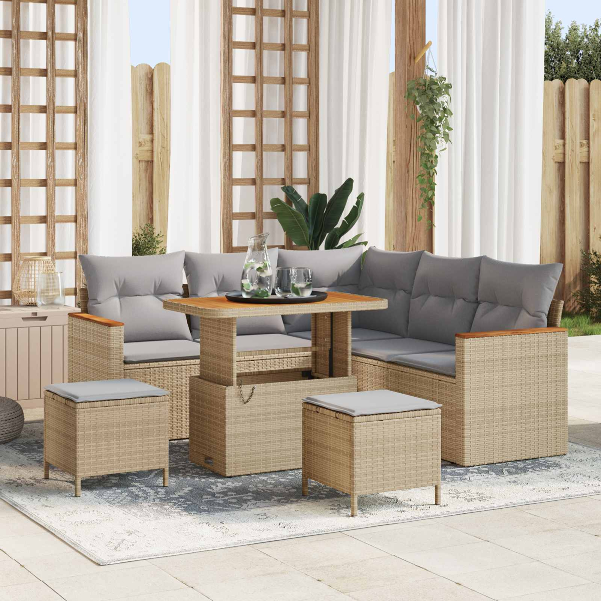 Ein beiger Rattansofa-Set mit Tisch, Hockern und grauen Kissen auf einer Terrasse.
