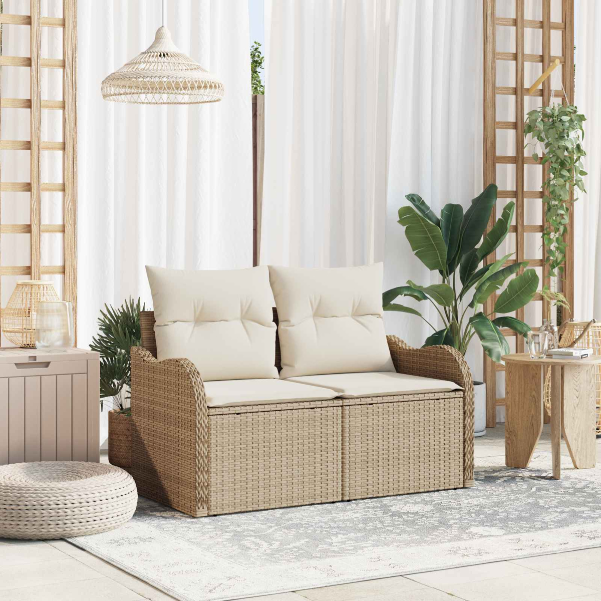 Ein beigefarbenes Rattan-Sofa mit Kissen steht auf einer Veranda mit Pflanzen und einem Holztisch.