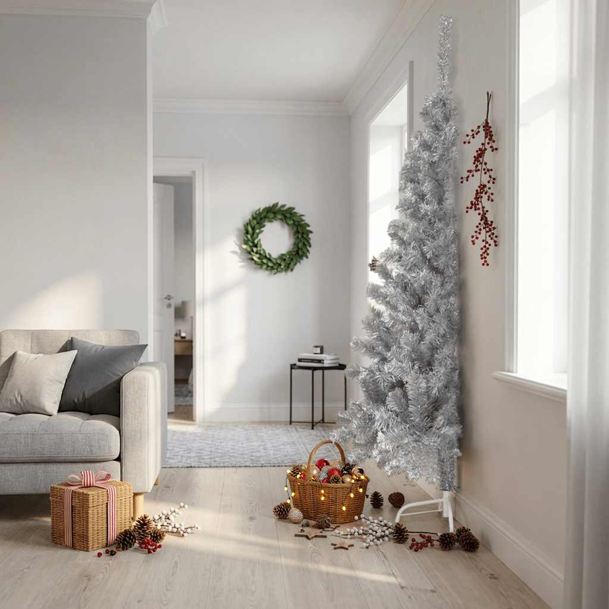 Ein schlanker silberner Lametta-Weihnachtsbaum steht in einem Raum mit Sofa, Geschenk, Kranz und Korb.