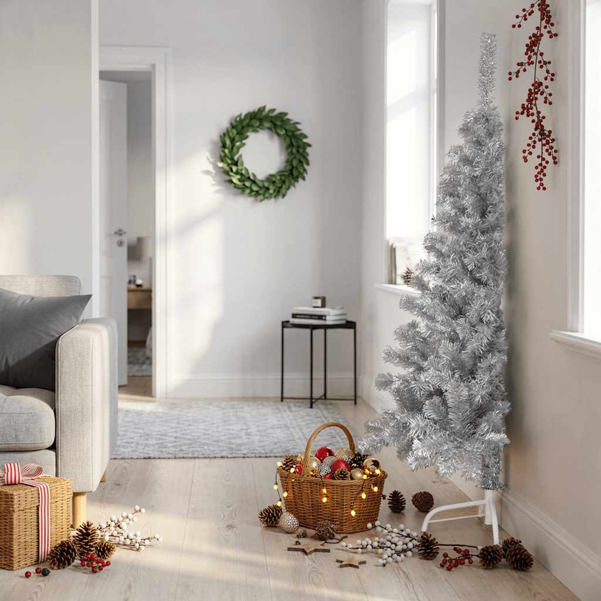 Ein silberner Weihnachtsbaum steht neben einem Korb mit Schmuck und Lichtern.