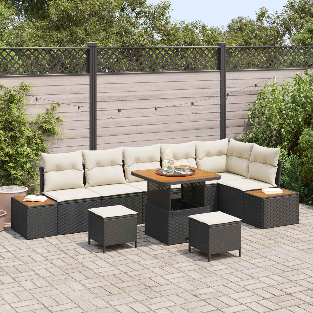 Ein dunkles Rattan-Lounge-Set mit beigen Kissen auf einer gepflasterten Terrasse.