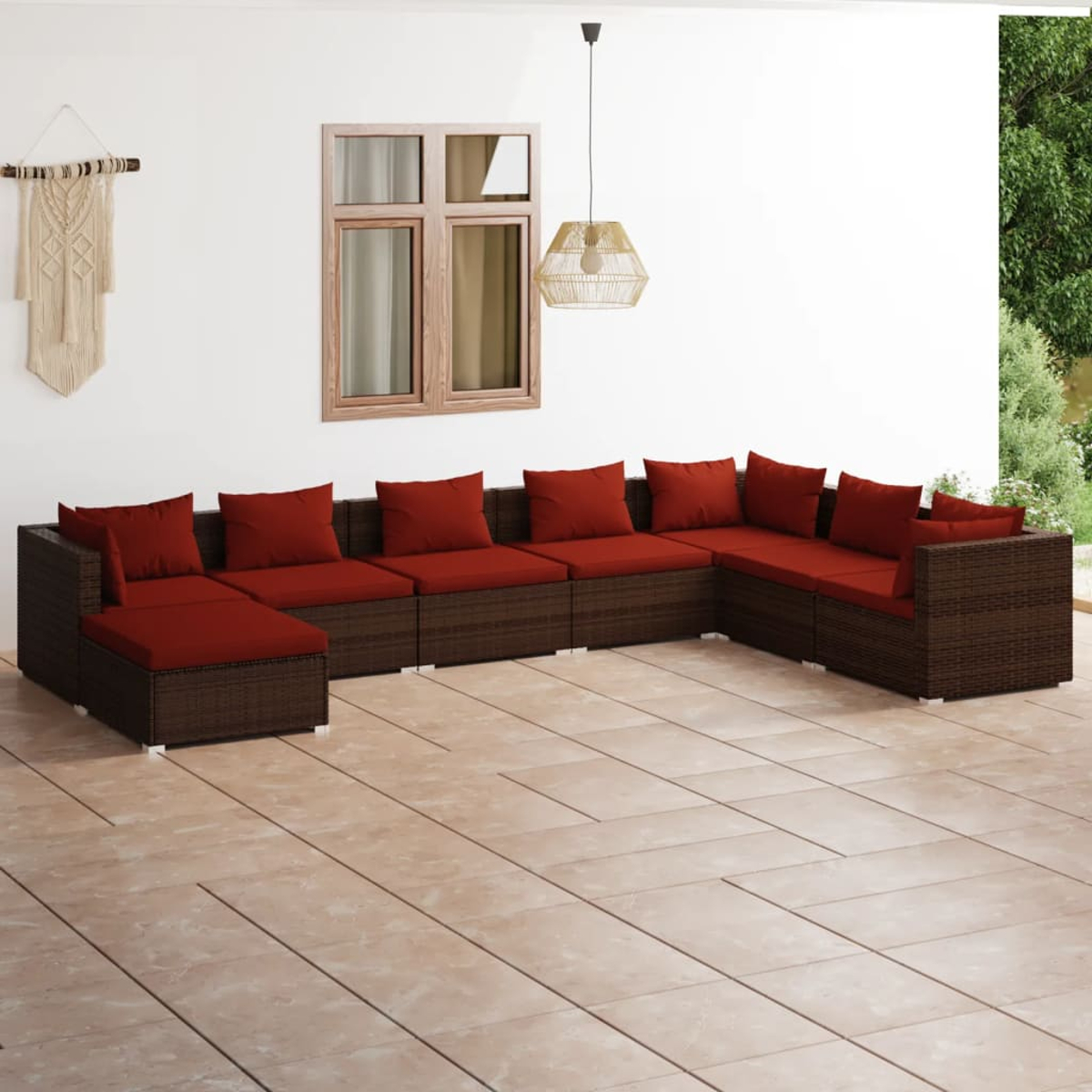 Ein dunkelbraunes Lounge-Sofa mit roten Kissen steht auf einer gefliesten Terrasse.