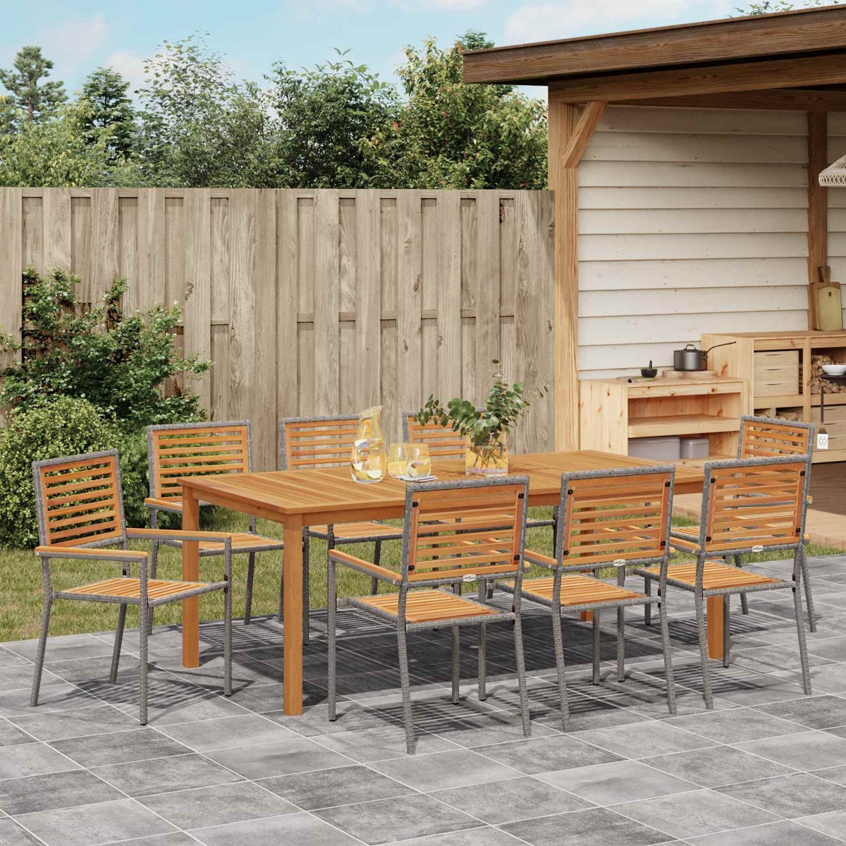Ein Holztisch und acht Stühle stehen auf einer gepflasterten Terrasse im Freien.