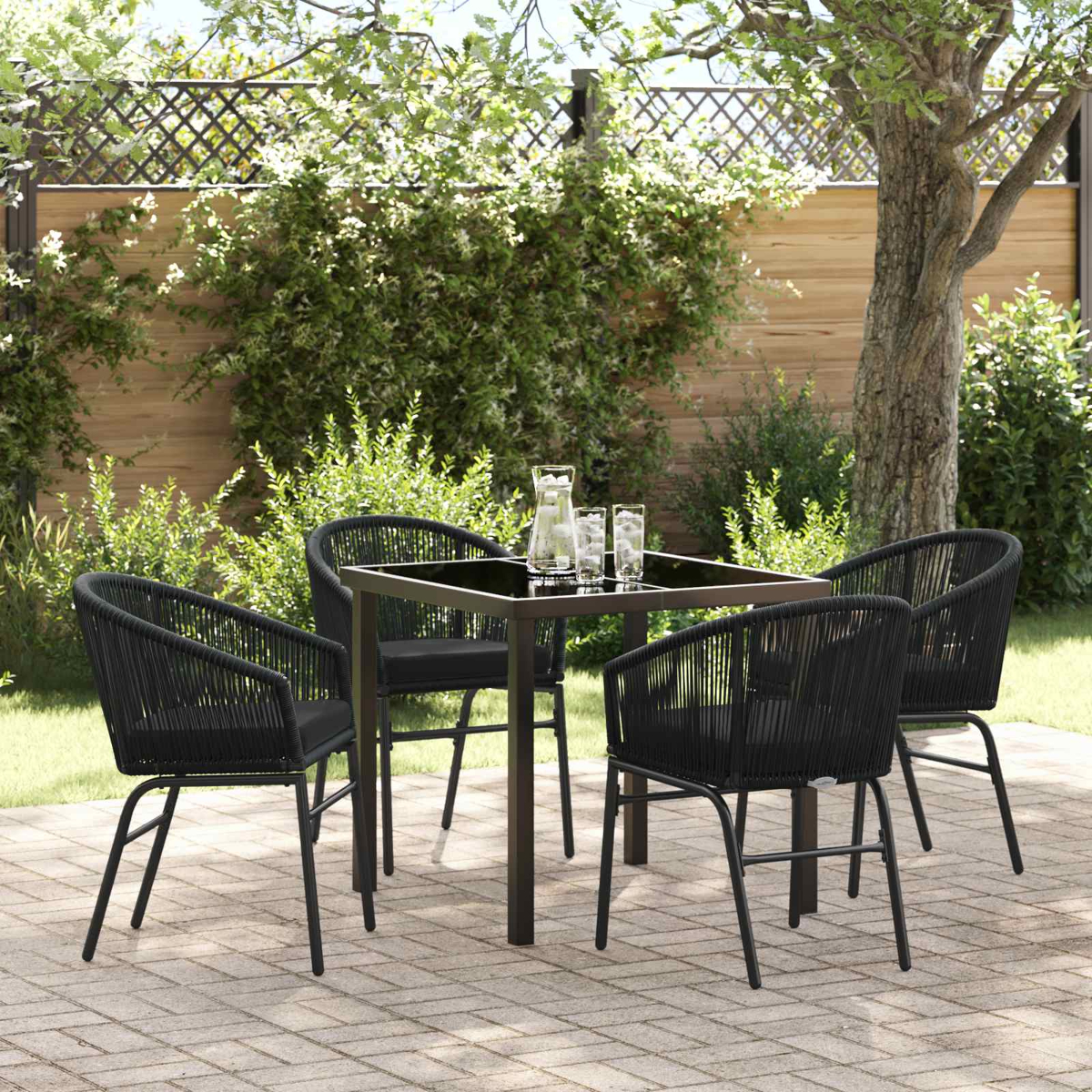 Ein schwarzer Tisch mit vier Stühlen im Garten, mit Wasser gefüllten Gläsern.
