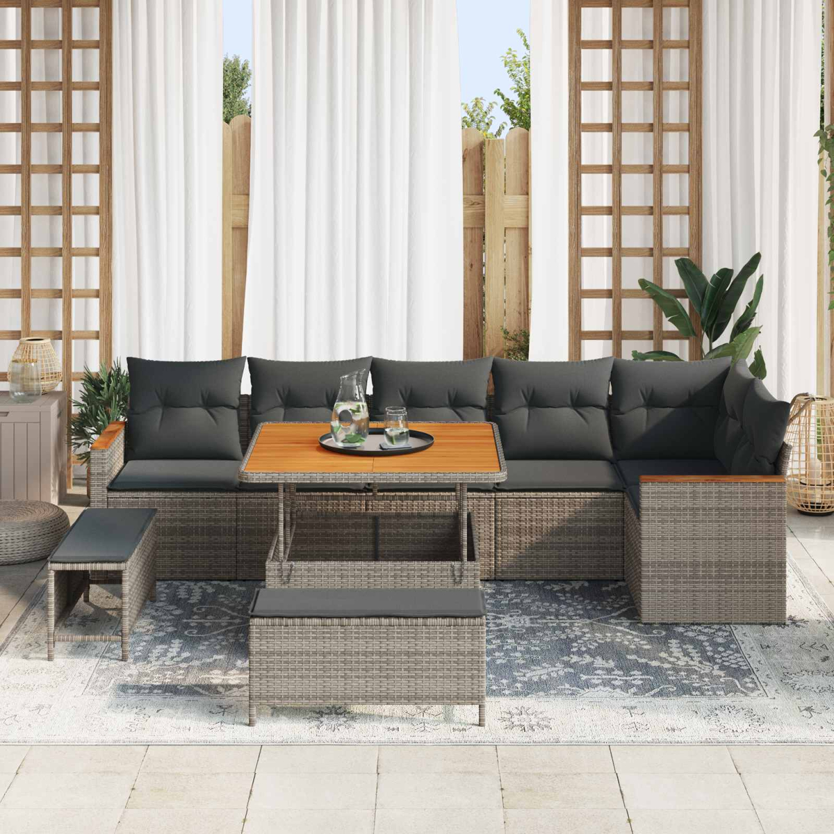 Graue Rattan-Lounge-Möbel mit Kaffeetisch und Beistelltischen auf einem Teppich.