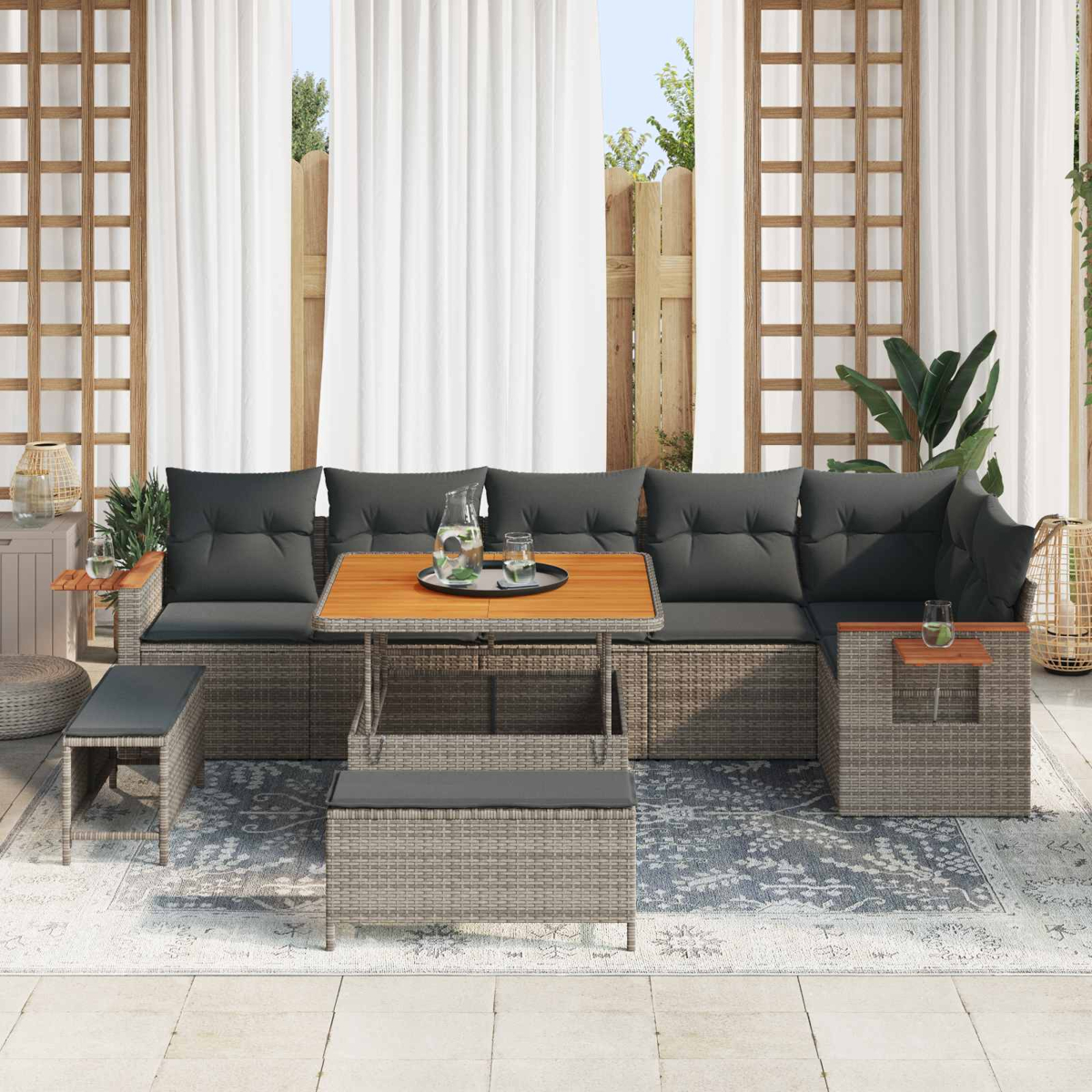 Ein graues Rattan-Sofaset mit Tisch und Hockern auf einer Veranda.