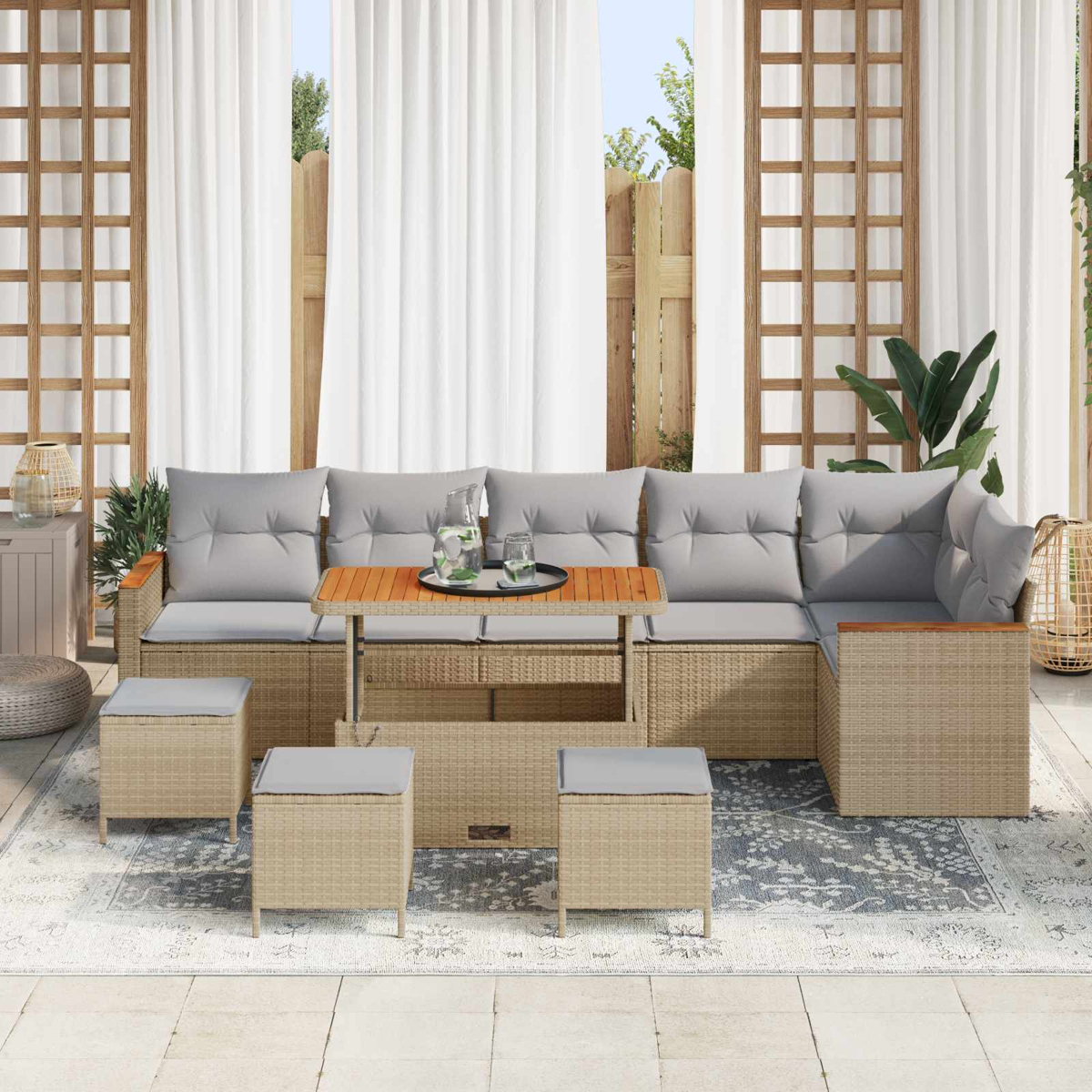 Geflochtene Lounge-Ecke mit Kaffeetisch, Sesseln und grauen Kissen auf einer Terrasse.