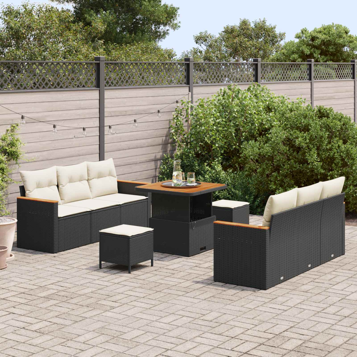 Ein dunkles Outdoor-Möbelset mit Sofas, Hockern und einem Tisch auf einer gepflasterten Terrasse.