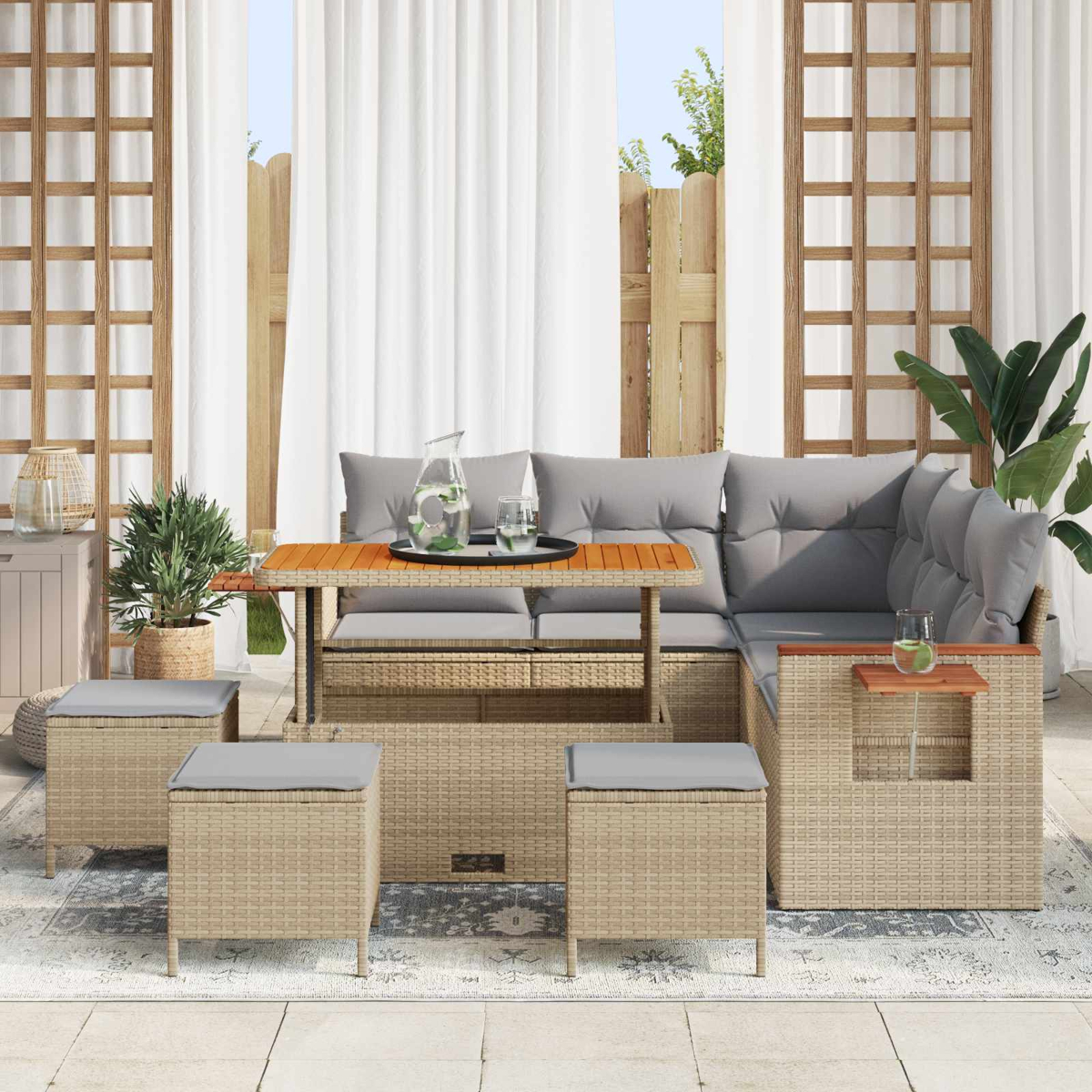 Geflochtenes Lounge-Set mit Tisch, Kissen und Hockern auf einer Terrasse.