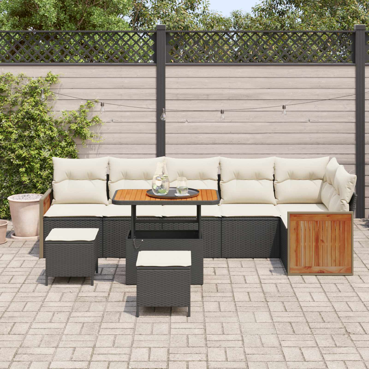 Ein Gartenmöbel-Set aus dunklem Rattan mit cremefarbenen Kissen und einem Holztisch.