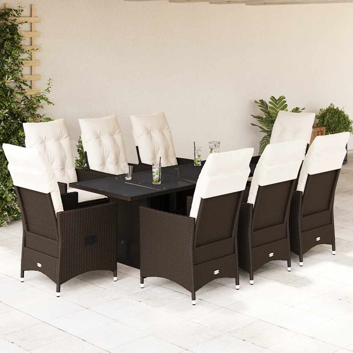 Dunkelbraune Rattan-Gartenmöbel mit weißen Kissen, Tisch mit Gläsern.