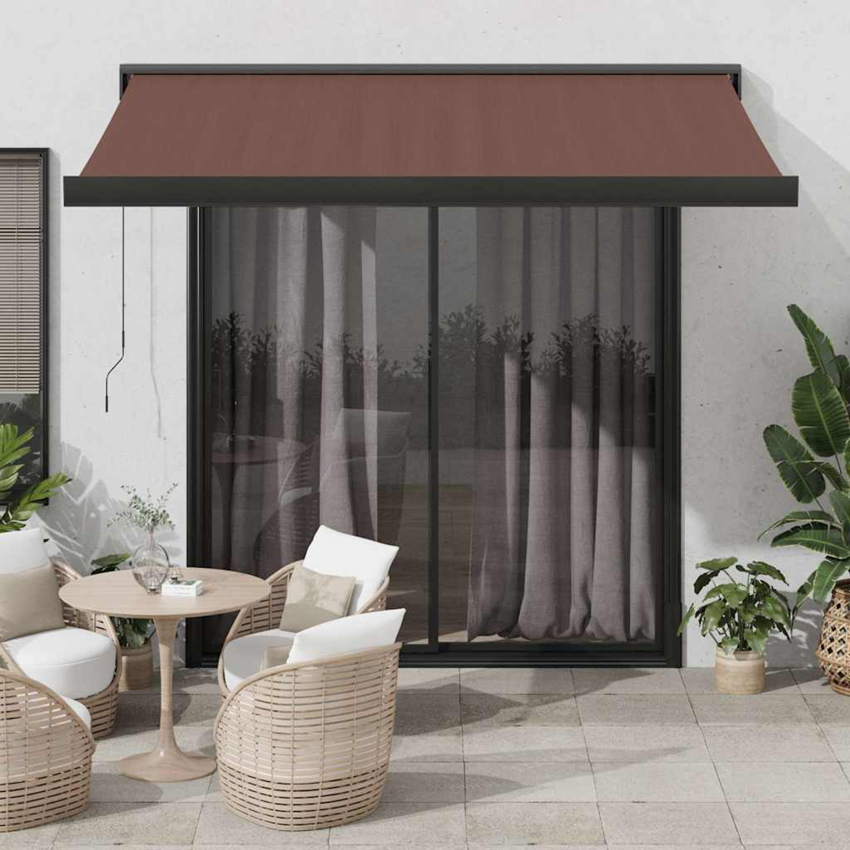 Patio esterno con tenda da sole marrone, porta a vetri, sedie in rattan, tavolo e piante.