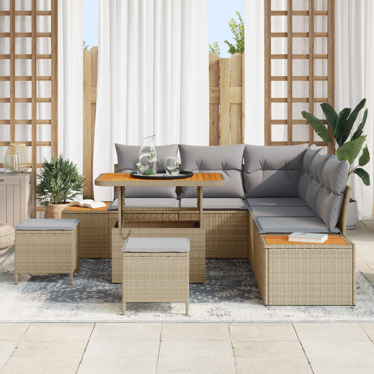 Geflochtenes Lounge-Set mit grauen Kissen, Tisch und Hockern auf einer Terrasse.