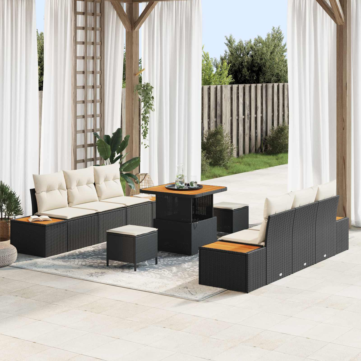Außenbereich mit schwarzer Rattansofa, Tisch und Hockern auf einer Terrasse.