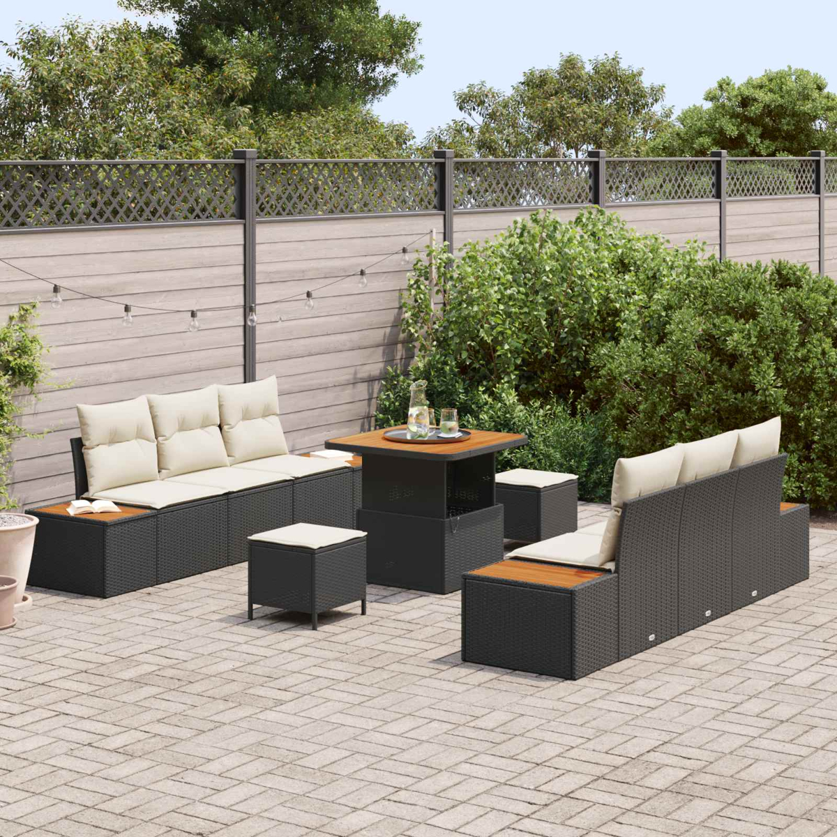 Dunkelgraue Rattan-Lounge-Möbel mit beigen Kissen auf gepflastertem Hof.
