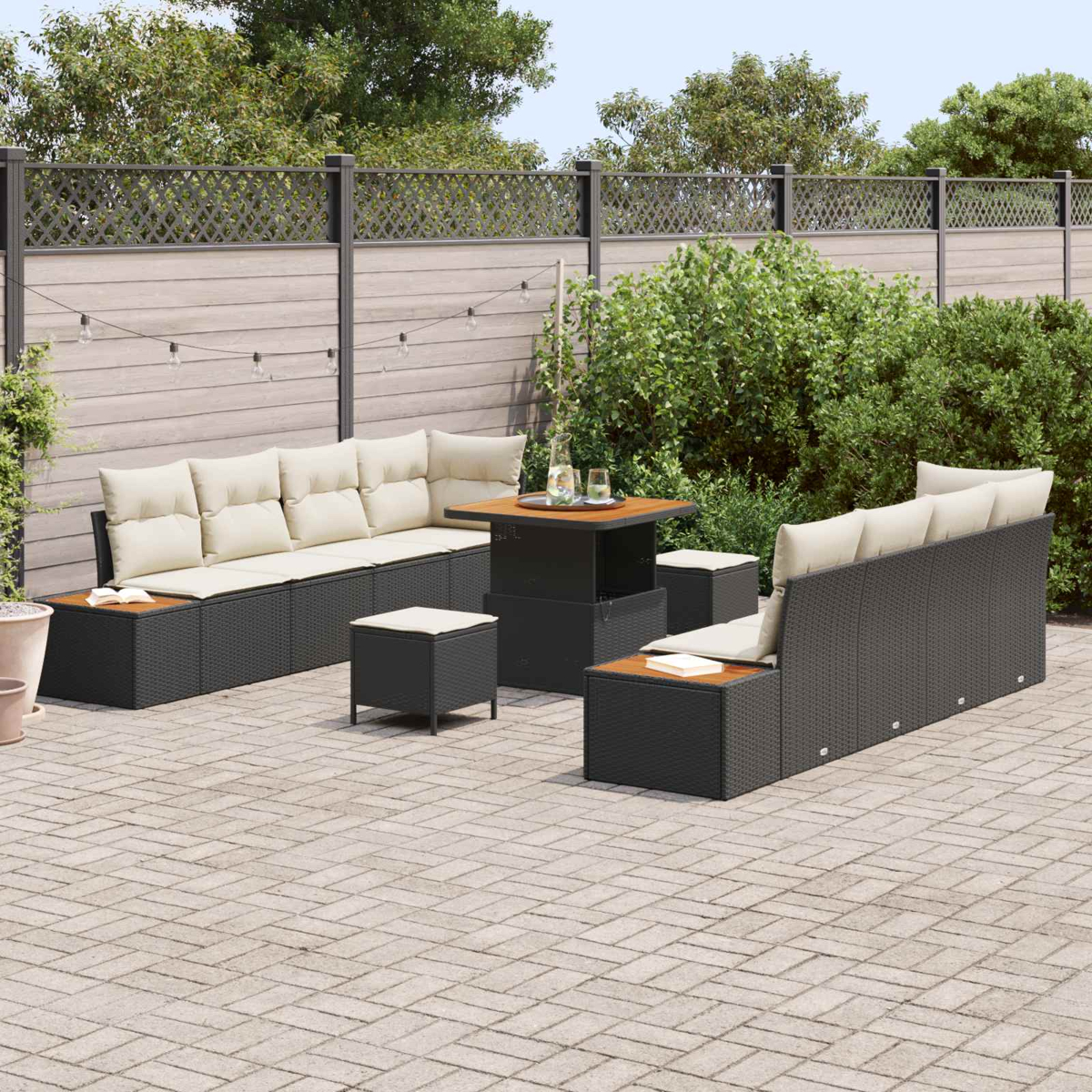 Un divano in rattan scuro con cuscini beige si trova su un patio pavimentato vicino a un tavolo.