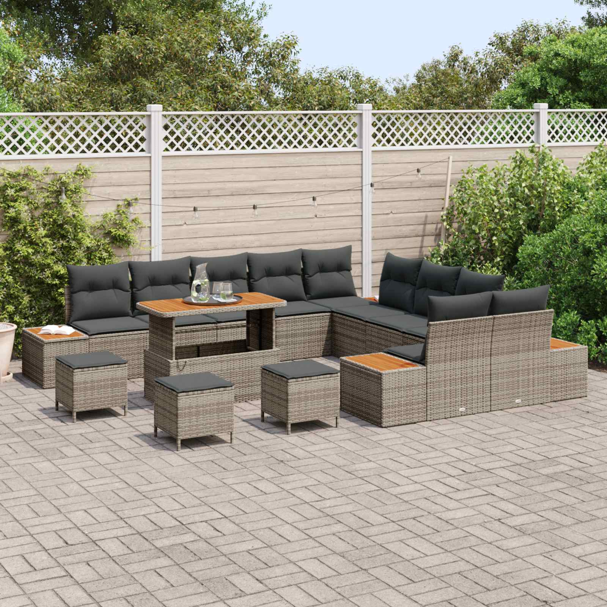 Un set di mobili da giardino in rattan con cuscini grigi su un patio pavimentato.