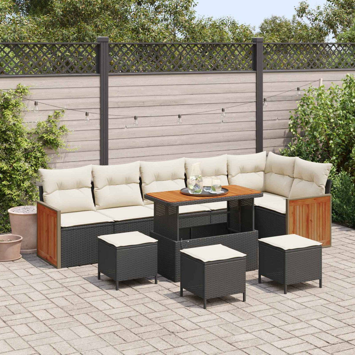 Gartenlounge mit Tisch und Hockern auf einem gepflasterten Hof, umgeben von Grün.