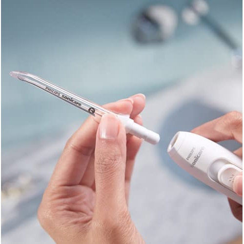 Una mano tiene un ugello trasparente per idropulsore con logo Philips Sonicare.