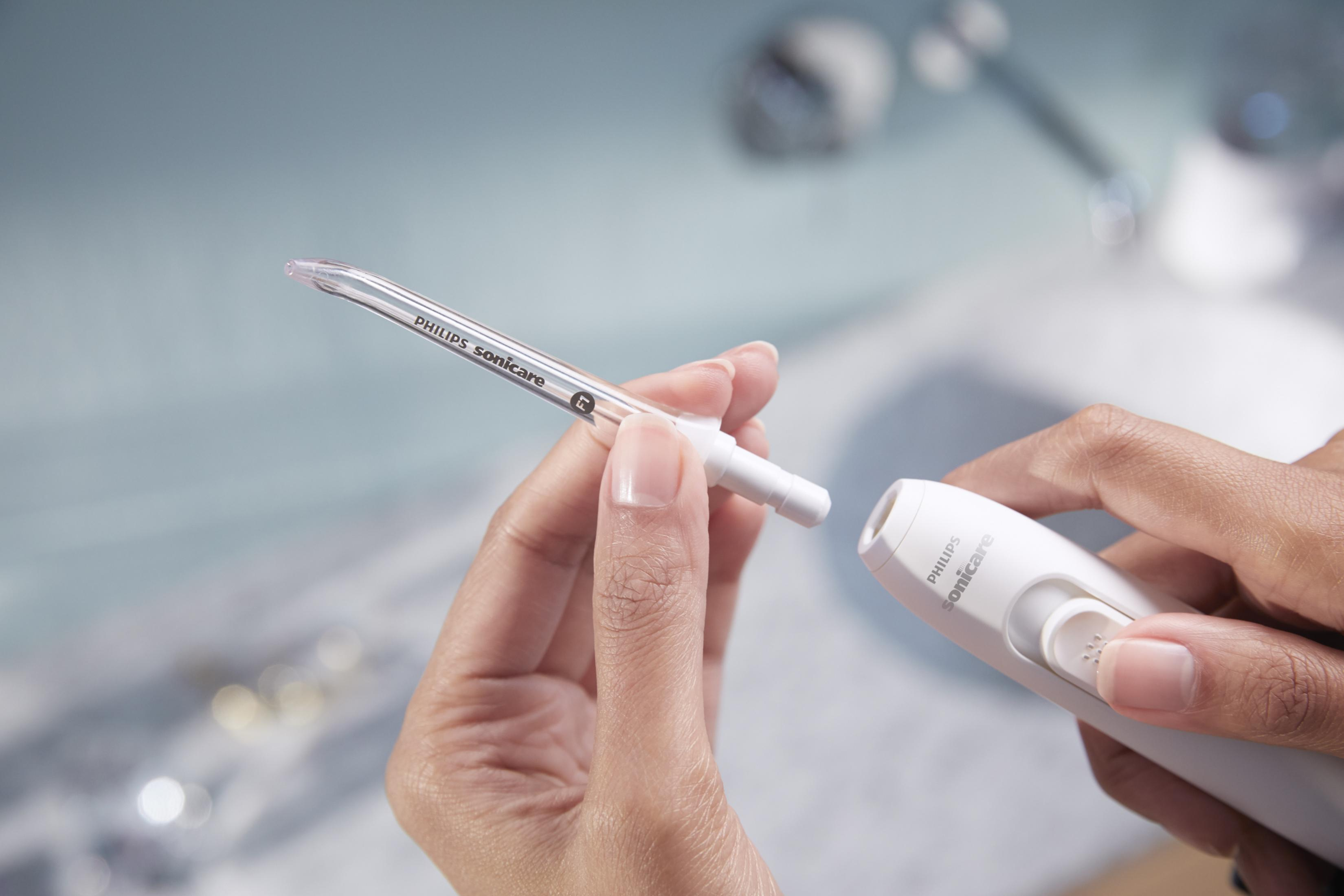Una mano tiene un ugello Philips Sonicare e il dispositivo. L'ugello viene inserito.